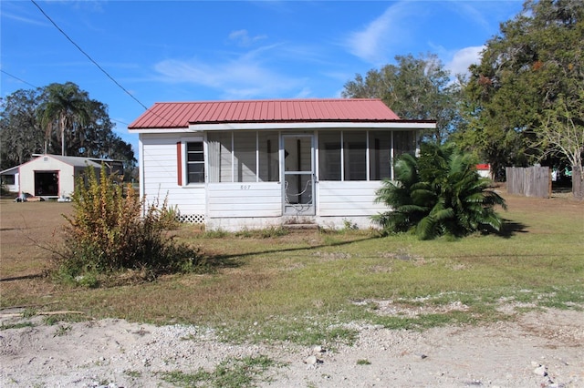 view of front of home featuring a sunroom and a front lawn