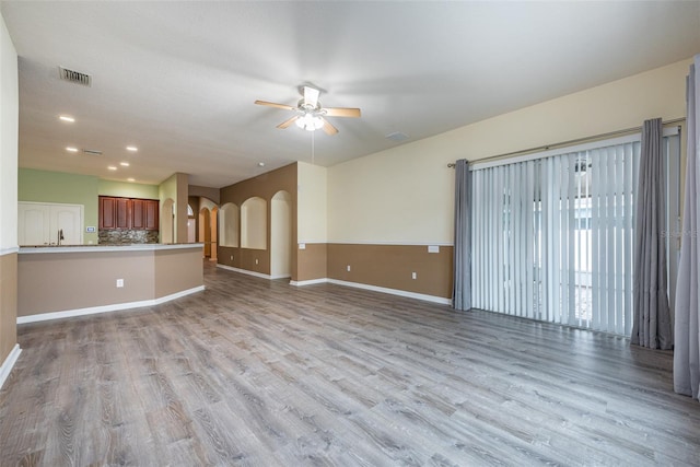 unfurnished living room featuring ceiling fan, sink, and light hardwood / wood-style flooring