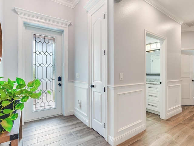 foyer with crown molding and light hardwood / wood-style floors