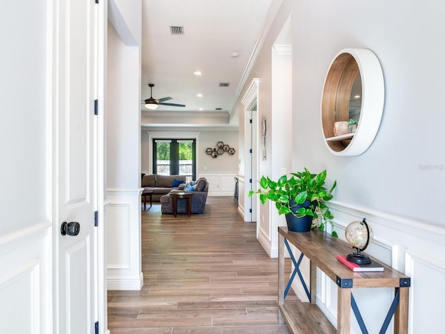 hall with ornamental molding, light wood-type flooring, and french doors