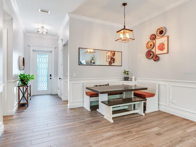 foyer entrance with ornamental molding, light hardwood / wood-style flooring, and a notable chandelier