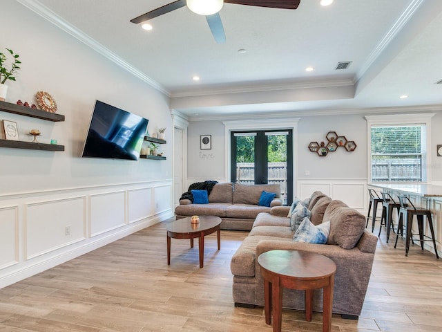 living room with crown molding, a healthy amount of sunlight, and light wood-type flooring