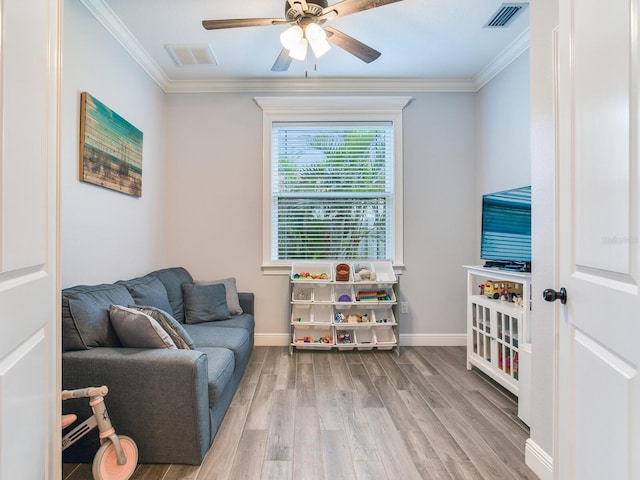 living area with ceiling fan, ornamental molding, and light wood-type flooring