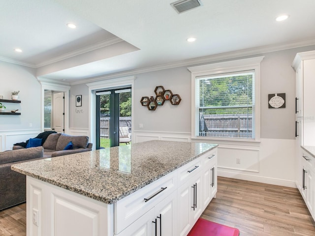 kitchen featuring light stone countertops, a center island, white cabinets, and light hardwood / wood-style floors