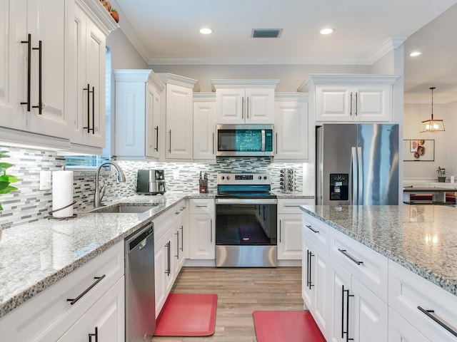 kitchen featuring sink, crown molding, appliances with stainless steel finishes, pendant lighting, and white cabinets