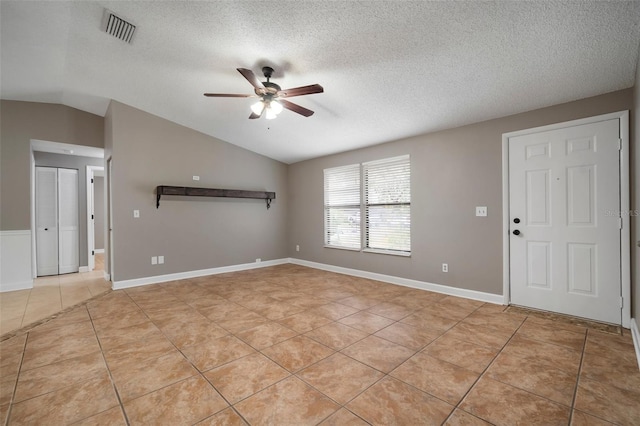 tiled spare room featuring ceiling fan, vaulted ceiling, and a textured ceiling