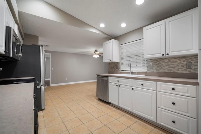 kitchen featuring sink, tasteful backsplash, light tile patterned floors, stainless steel appliances, and white cabinets