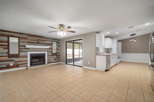 kitchen featuring pendant lighting, light tile patterned floors, white cabinets, vaulted ceiling, and stainless steel dishwasher