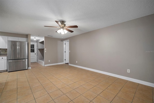 interior space with stainless steel refrigerator, ceiling fan, tasteful backsplash, white cabinets, and light tile patterned flooring