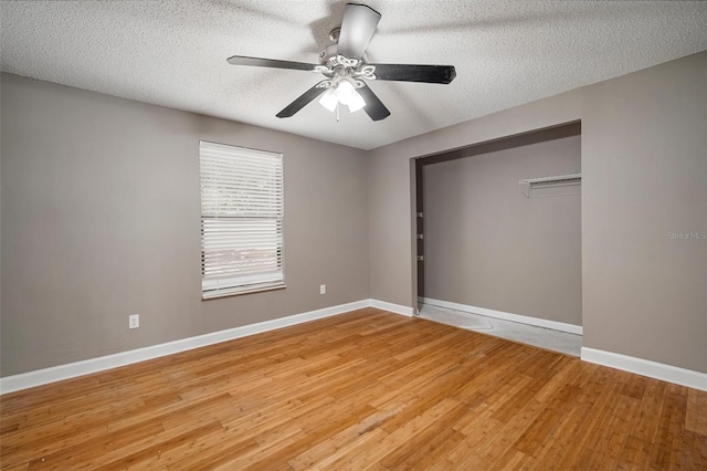 unfurnished bedroom featuring ceiling fan, hardwood / wood-style flooring, a closet, and a textured ceiling