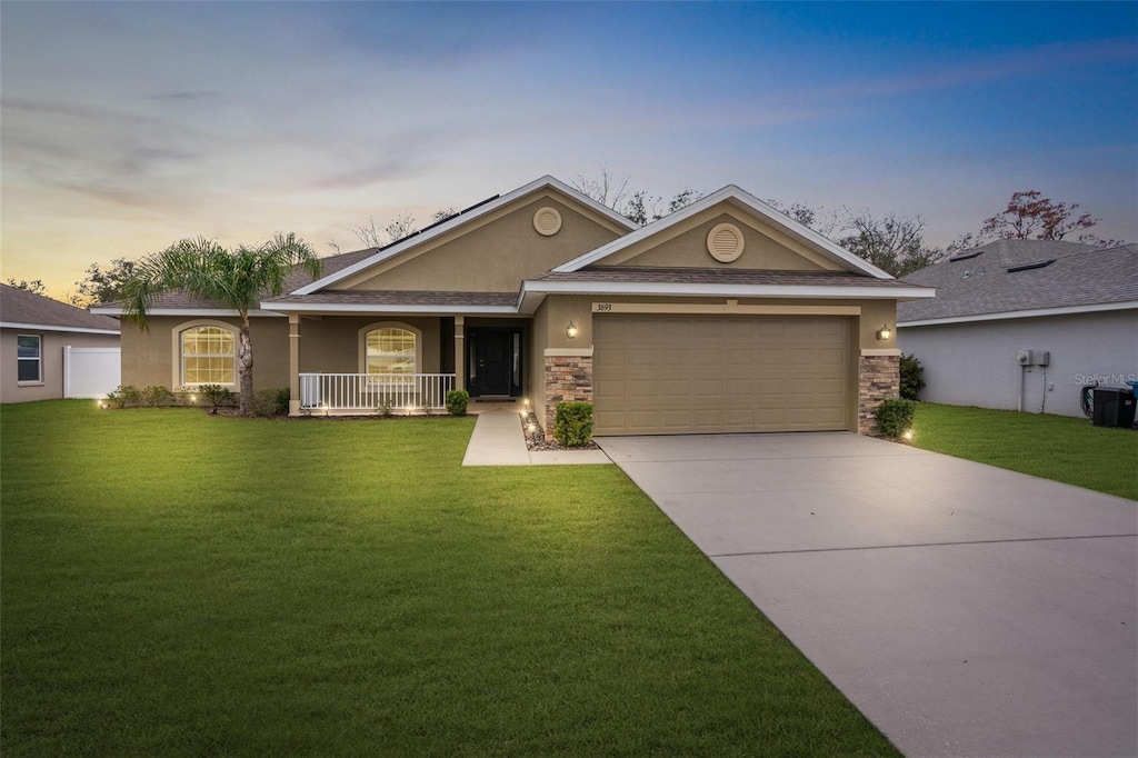 ranch-style home featuring a garage, a yard, and covered porch