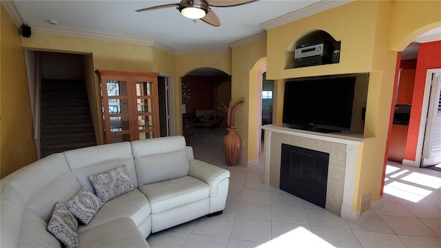 tiled living room with ceiling fan, ornamental molding, and a fireplace