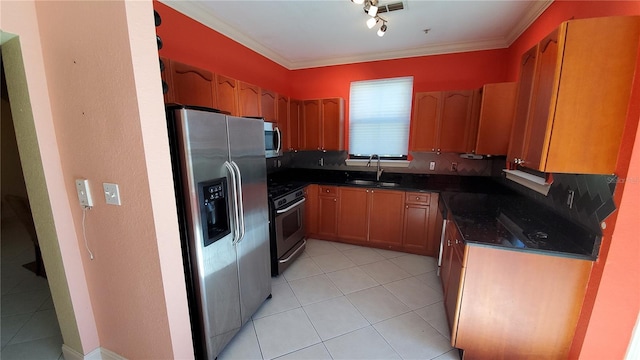 kitchen with appliances with stainless steel finishes, sink, dark stone countertops, ornamental molding, and light tile patterned floors