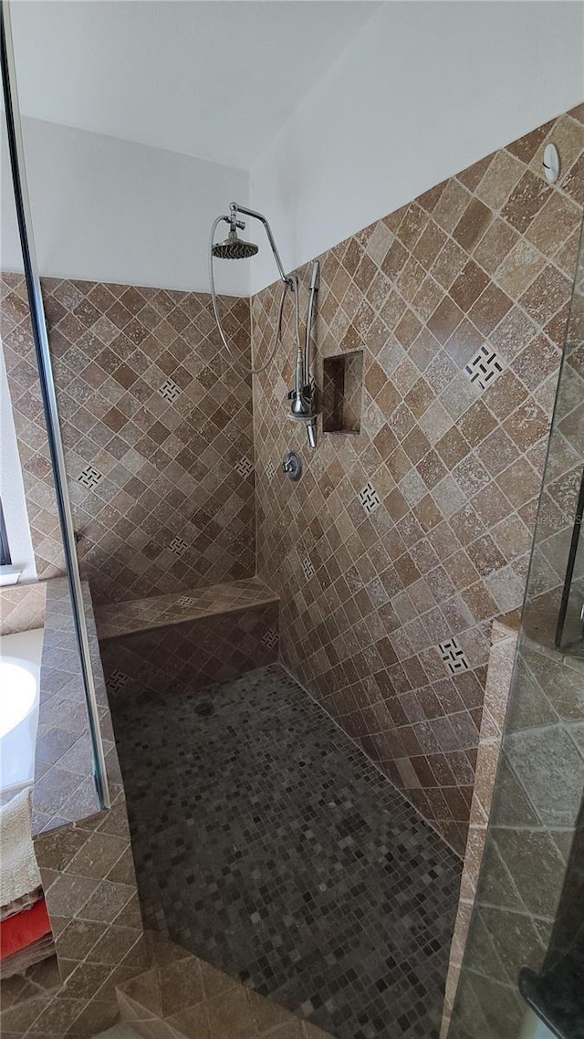 bathroom with tiled shower and tile patterned floors