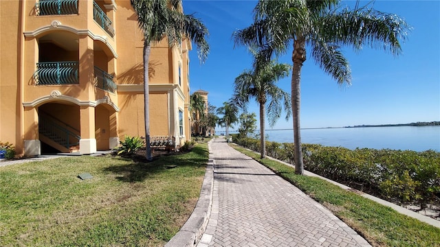 surrounding community with a water view and a yard