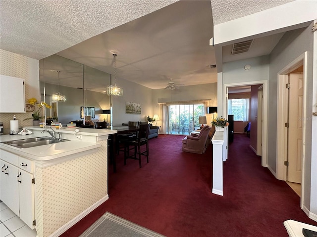 kitchen featuring pendant lighting, sink, light colored carpet, and white cabinets