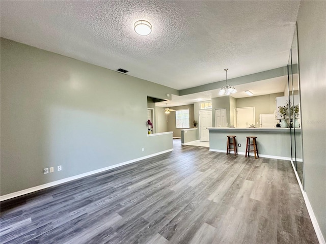 2116 Nantucket Dr Unit 19, Sun City Center, FL 33573 - unfurnished living room featuring dark wood finished floors, visible vents, baseboards, a textured ceiling, and a notable chandelier
