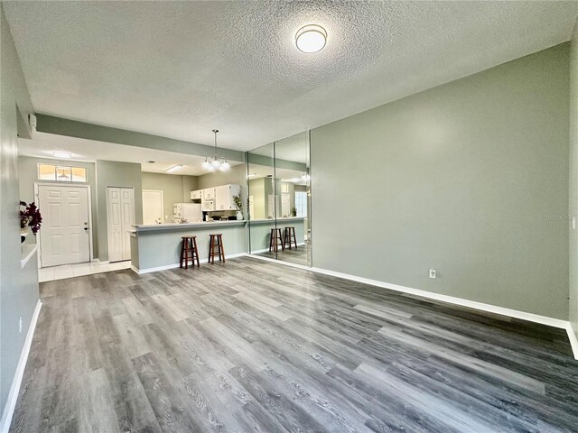 2116 Nantucket Dr Unit 19, Sun City Center, FL 33573 - unfurnished living room with dark wood-style floors, a textured ceiling, a healthy amount of sunlight, baseboards, and an inviting chandelier