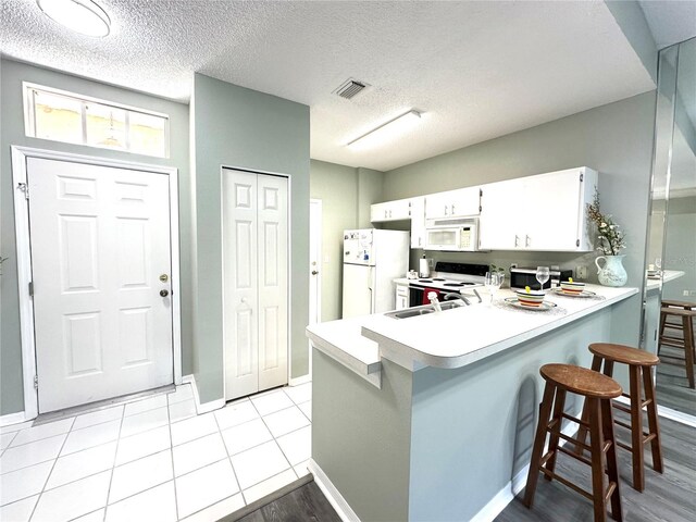 2116 Nantucket Dr Unit 19, Sun City Center, FL 33573 - kitchen with a peninsula, visible vents, white appliances, and light countertops