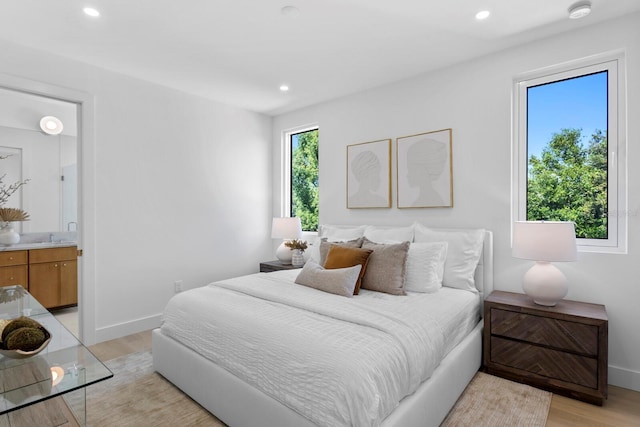 bedroom featuring light wood-type flooring and ensuite bathroom