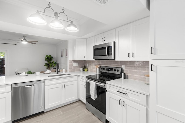 kitchen with appliances with stainless steel finishes, decorative light fixtures, sink, white cabinets, and decorative backsplash