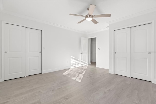 unfurnished bedroom featuring multiple closets, crown molding, ceiling fan, and light wood-type flooring