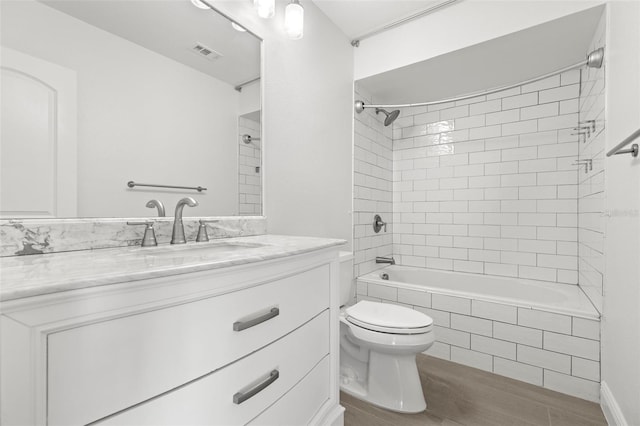 full bathroom with vanity, wood-type flooring, toilet, and tiled shower / bath