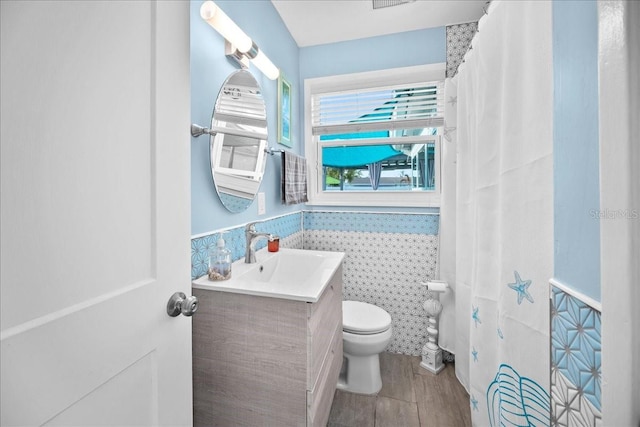 bathroom with vanity, toilet, hardwood / wood-style floors, and tile walls