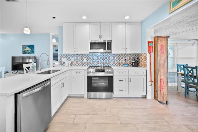 kitchen with sink, appliances with stainless steel finishes, kitchen peninsula, pendant lighting, and white cabinets