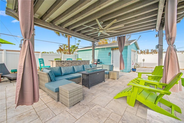 view of patio / terrace featuring a fenced backyard, an outdoor structure, a ceiling fan, and an outdoor living space with a fire pit