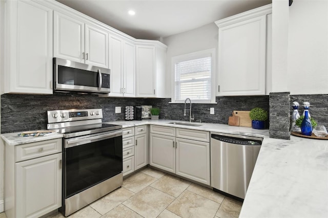 kitchen featuring sink, backsplash, white cabinets, and appliances with stainless steel finishes