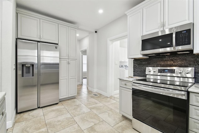 kitchen with backsplash, appliances with stainless steel finishes, light tile patterned flooring, and white cabinets