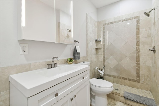 bathroom with tiled shower, vanity, and toilet