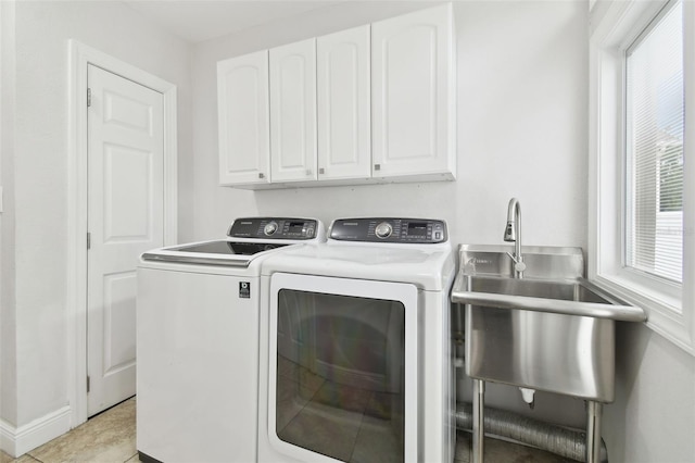 clothes washing area featuring cabinets, sink, light tile patterned floors, and washing machine and clothes dryer