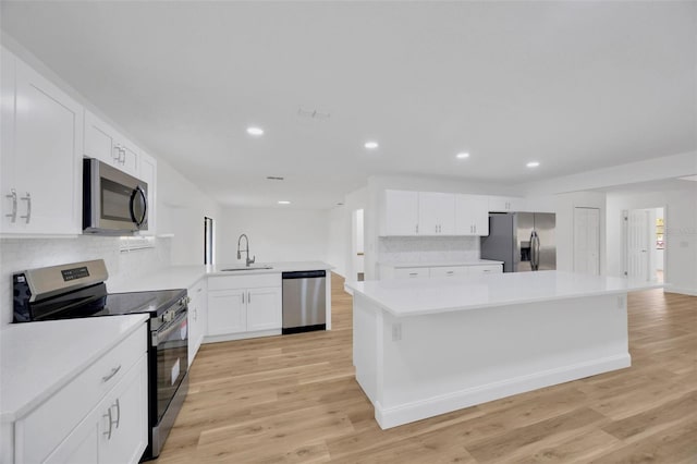 kitchen featuring sink, appliances with stainless steel finishes, white cabinetry, kitchen peninsula, and light wood-type flooring