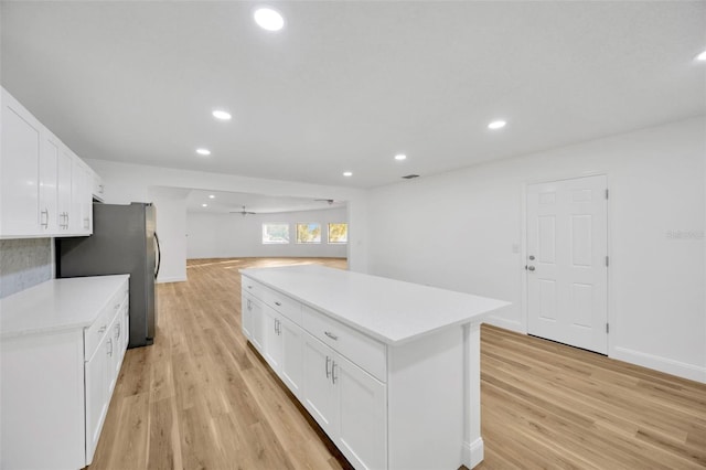 kitchen featuring white cabinetry, ceiling fan, a kitchen island, and light hardwood / wood-style flooring