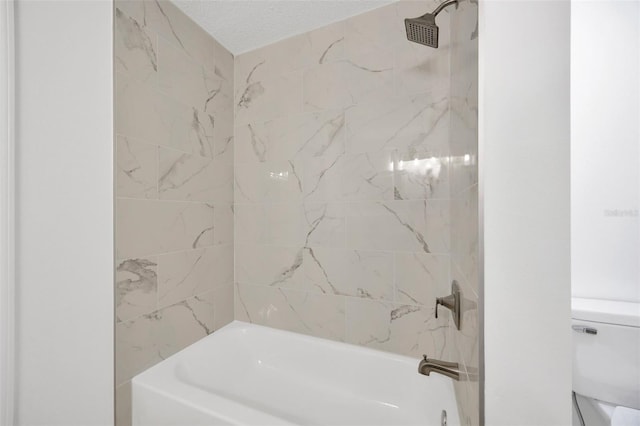 bathroom featuring toilet, tiled shower / bath combo, and a textured ceiling