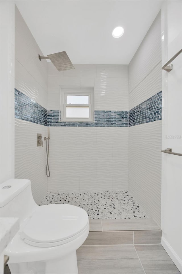 bathroom featuring a tile shower and toilet