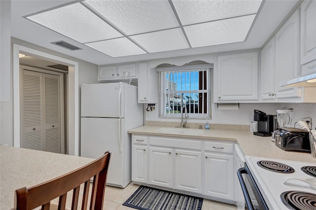 kitchen with sink, white appliances, light tile patterned floors, and white cabinets