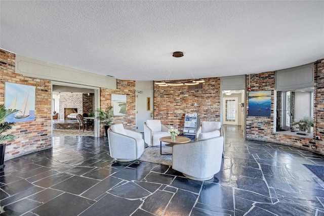 living room featuring brick wall, a fireplace, and a textured ceiling