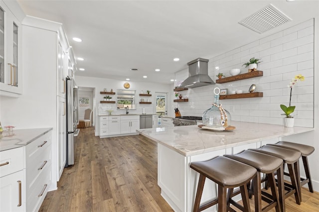 kitchen with extractor fan, stainless steel appliances, kitchen peninsula, and white cabinets