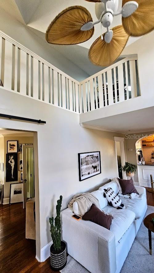 living room featuring ceiling fan, a towering ceiling, a barn door, and dark hardwood / wood-style floors