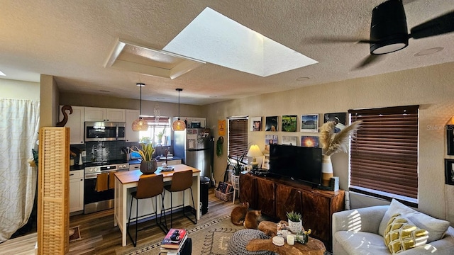 living room with wood-type flooring, a textured ceiling, and ceiling fan