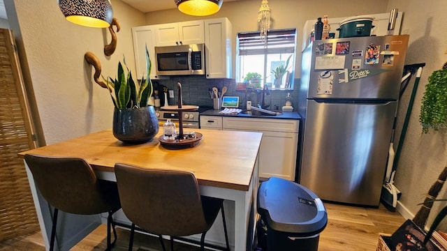 kitchen with stainless steel appliances, butcher block countertops, decorative backsplash, and white cabinets