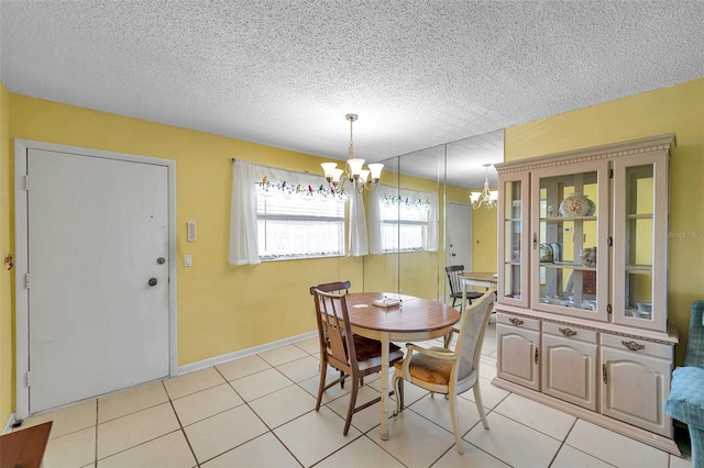 tiled dining area with a chandelier and a textured ceiling