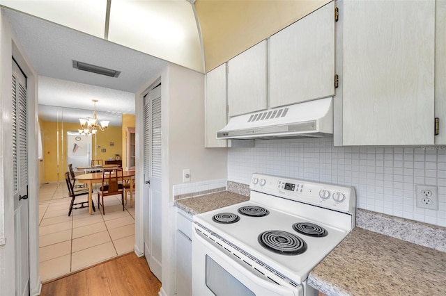 kitchen with white electric stove, a notable chandelier, pendant lighting, and white cabinets