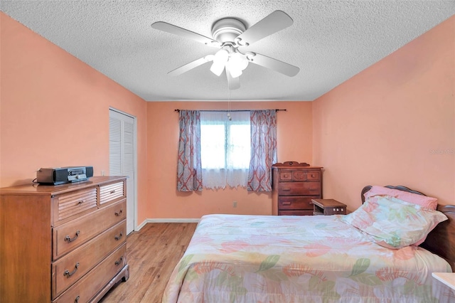 bedroom with ceiling fan, light hardwood / wood-style floors, a closet, and a textured ceiling