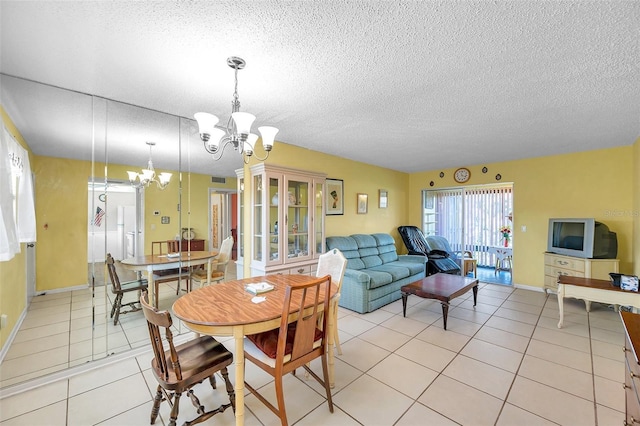 dining space featuring a notable chandelier, a textured ceiling, baseboards, and light tile patterned floors