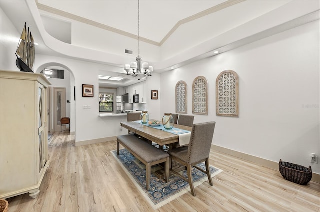 dining room with lofted ceiling, crown molding, a tray ceiling, a notable chandelier, and light hardwood / wood-style floors