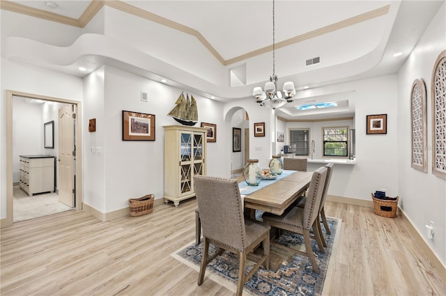 dining area featuring a notable chandelier, vaulted ceiling, ornamental molding, and light wood-type flooring